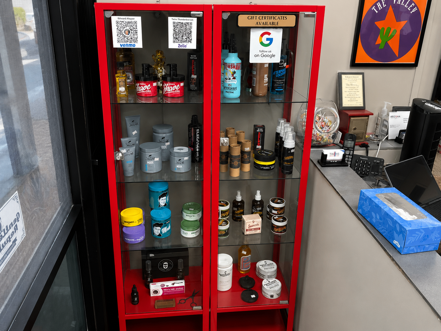Red retail product display cabinet inside Twins Barber Shop front counter area